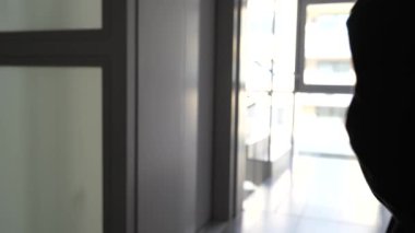 Bulanık siluet genç kadın koridorda asansör çağrı düğmesine basıyor. Bir apartmanda modern asansör