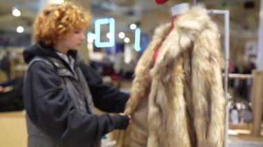 Mağazada moda kürk giyen kızıl saçlı çekici genç bir kadının portresi. pozitif gülümseme