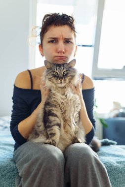 Çekici genç bir kadının portresi. Kucağında gri tüylü evcil bir kedi tutuyor. Birlikte vakit geçiriyorlar.