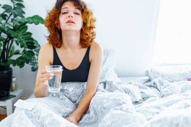 Baş ağrısı, akşamdan kalma, bulantı, grip ve makyajlı genç bir kadın.