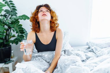 Baş ağrısı, akşamdan kalma, bulantı, grip ve makyajlı genç bir kadın.