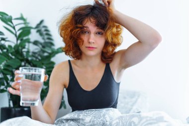 Baş ağrısı, akşamdan kalma, bulantı, grip ve makyajlı genç bir kadın.