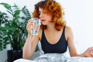 Baş ağrısı, akşamdan kalma, bulantı, grip ve makyajlı genç bir kadın.