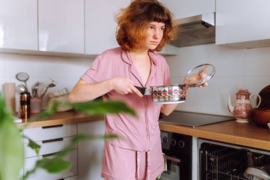 Bulaşık makinesi kullanan genç bir kadın bulaşık yıkıyor.