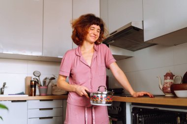 Bulaşık makinesi kullanan genç bir kadın bulaşık yıkıyor.