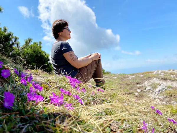 Velika Planina, Slovenya. 05.15.2022. Kadın dağlardaki dağlık köyün manzarasını seviyor. Velika Planina. Büyük Pasture Platosu. Slovenya. Kulübe ya da ev. Bahar manzarası