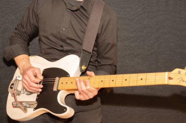 Vaduz, Lihtenştayn, 23 Aralık 2022 Müzisyen, Japonya 'da üretilen büyük bir tremolo sistemiyle beyaz Fender Telecaster elektro gitar çalıyor.