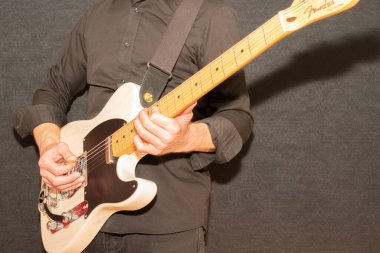 Vaduz, Lihtenştayn, 23 Aralık 2022 Müzisyen, Japonya 'da üretilen büyük bir tremolo sistemiyle beyaz Fender Telecaster elektro gitar çalıyor.