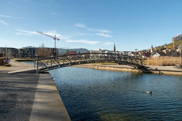 stock image Unteraegeri, Switzerland, February 20, 2023 Small pedestrian bridge across a canal at the lake Aegerisee