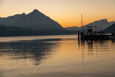 Görünmez, Canton Bern, İsviçre, 12 Şubat 2023. Thun Gölü kıyısından gün batımından hemen sonra fantastik alp manzarası. Arka planda Niesen Dağı.