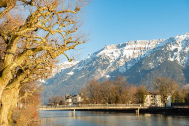 Interlaken, İsviçre, 10 Şubat 2023. Şehir merkezindeki Aare nehri boyunca uzanan su yolu. Arka planda görkemli Alpler var.