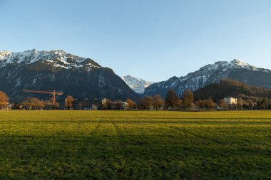 Interlaken, İsviçre, 10 Şubat 2023 Yeşil bir park ve şehir merkezinde büyüleyici bir dağ manzarası