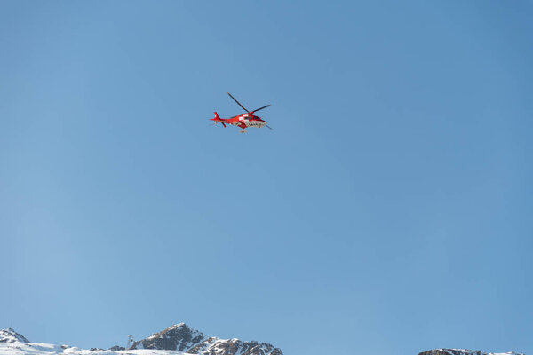 Saint Moritz, Switzerland, February 21, 2023 REGA air ambulance helicopter in the blue sky