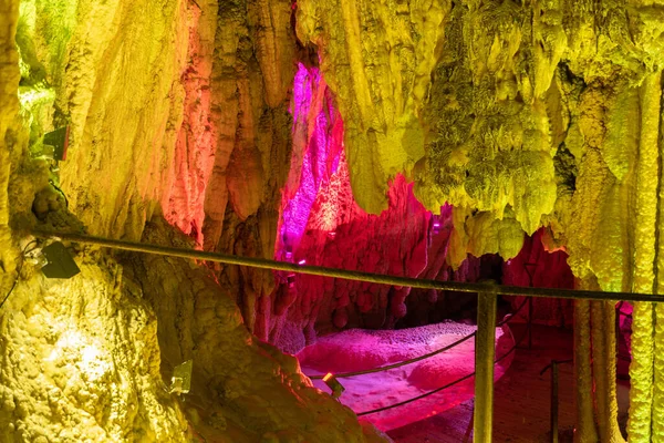 Stock image Baar, Switzerland, April 29, 2023 Incredible fascinating rock formation and a small lake inside the Hoellengrotten cave illuminated with colorful lights