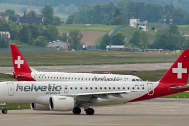 Zürih, İsviçre, 19 Mayıs 2023 HB-JVP Helvetic Airways Embraer E-190LR uçağı 10 numaralı pistten kalkıyor.