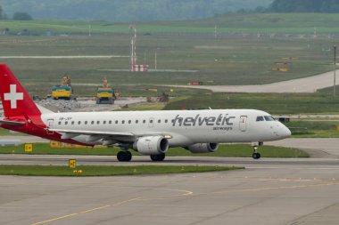 Zürih, İsviçre, 19 Mayıs 2023 HB-JVP Helvetic Airways Embraer E-190LR uçağı 10 numaralı pistten kalkıyor.