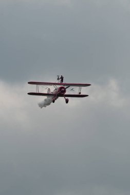 Speck-Fehraltorf, Zürih, İsviçre, 2 Temmuz 2023 N-450D Boeing PT-13D tarihi çift katlı uçak hava gösterisi sırasında kanat yürüyüşü yapan bir kadınla