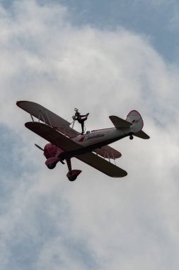 Speck-Fehraltorf, Zürih, İsviçre, 2 Temmuz 2023 N-450D Boeing PT-13D tarihi çift katlı uçak hava gösterisi sırasında kanat yürüyüşü yapan bir kadınla