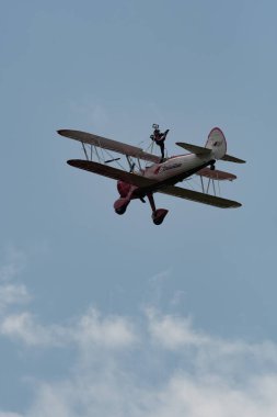 Speck-Fehraltorf, Zürih, İsviçre, 2 Temmuz 2023 N-450D Boeing PT-13D tarihi çift katlı uçak hava gösterisi sırasında kanat yürüyüşü yapan bir kadınla