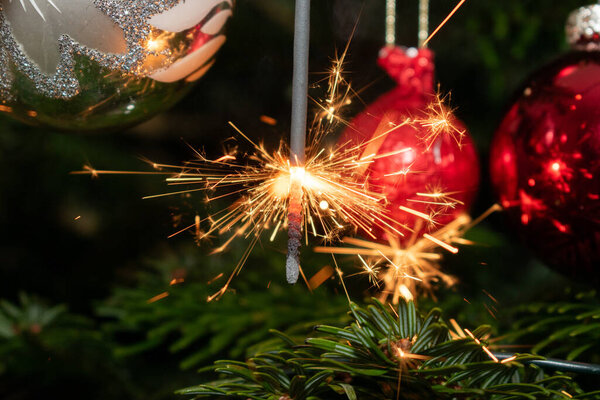 Ruggell, Liechtenstein, December 24, 2022 Burning bengal fire during christmas celebration on a fir tree