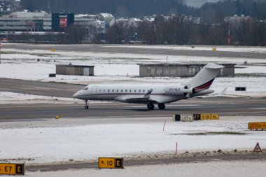 Zürih, İsviçre, 6 Aralık 2023 CS-GLD Bombardier Global 6000 uçağı kış mevsiminde park yerine doğru ilerliyor.