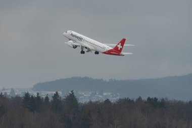 Zürih, İsviçre, 6 Aralık 2023 HB-AZG Helvetic Havayolları Embraer E-190-E2 uçağı kış mevsiminde 28. pistten kalkıyor.