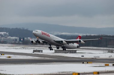 Zürih, İsviçre, 6 Aralık 2023 HB-JMI İsviçreli uluslararası havayolu Airbus A340-313X uçağı kış mevsimi 16. pistten kalkıyor.