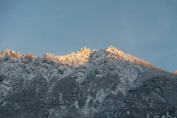 Vaduz, Lihtenştayn, 3 Aralık 2023 Karla kaplı dağların zirvesinde son güneş ışınları