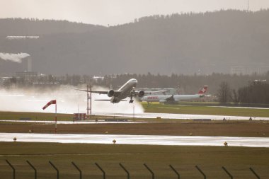 Zürih, İsviçre, 4 Ocak 2024 9V-SWV Singapur Havayolları Boeing 777-312ER uçağı 32 nolu pistten yağmur yağmuru sırasında kalkıyor.