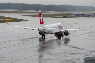 Zürih, İsviçre, 17 Ocak 2024 HB-JBF İsviçre Airbus A220-100 veya Bombardier CS-100 uçakları bir yağmur yağışı sırasında apron boyunca çekilir.