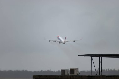 Zürih, İsviçre, 18 Ocak 2024 HB-JMC Edelweiss Air Airbus A340-313X hava aracı 34 numaralı pistten bir yağmur yağışı sırasında kalkıyor.
