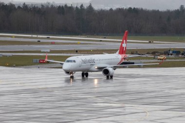 Zürih, İsviçre, 18 Ocak 2024 HB-JVX Helvetic Airways Embraer E190LR uçağı yağmur altında kapıya doğru ilerliyor.