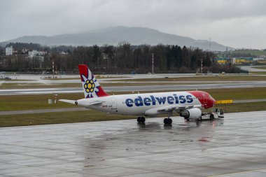 Zürih, İsviçre, 18 Ocak 2024 HB-JLS Edelweiss Air Airbus A320-214 tipi uçak, bir yağmur yağışı sırasında apron boyunca çekildi.
