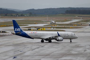 Zürih, İsviçre, 18 Ocak 2024 SE-RSK SAS İskandinavya Hava Yolları Embraer E195LR uçağı yağmur yağarken kalkış pozisyonuna geçiyor