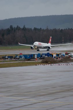 Zürih, İsviçre, 18 Ocak 2024 HB-JHL İsviçreli uluslararası havayolu Airbus A330-343 uçağı yağmurlu bir sağanak sırasında 16 numaralı pistten kalkıyor.