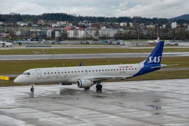 Zürih, İsviçre, 18 Ocak 2024 SE-RSK SAS İskandinav havayolları Embraer E195LR uçakları bir yağmur yağmuru sırasında önlük boyunca taksicilik yapıyor