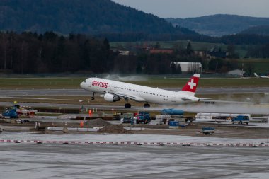 Zürih, İsviçre, 18 Ocak 2024 HB-IOF İsviçreli uluslararası havayolu Airbus A321-111 uçağı, 28 numaralı pistten yağmur yağışlı bir havada kalkıyor.