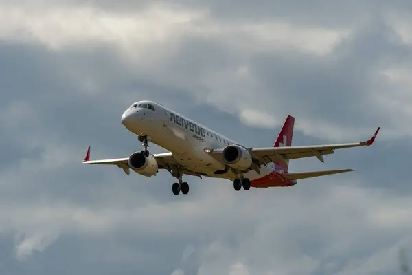 Stock image Zurich, Switzerland, June 16, 2024 HB-JVO Helvetic Airways Embraer E190LR aircraft is landing on runway 14