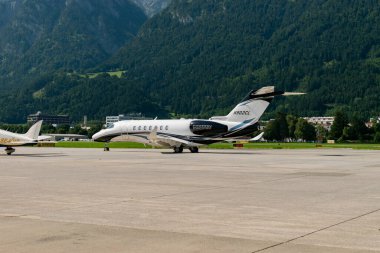 Innsbruck, Avusturya, 30 Temmuz 2024 Cessna 700 Citation Longitude uçağı önlüğe park ediyor.