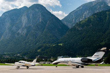 Innsbruck, Austria, July 30, 2024 Cessna 700 Citation Longitude and a Piper PA-28-181 aircraft are parking on the apron clipart