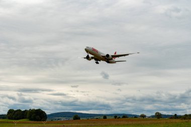 Zürih, İsviçre, 14 Eylül 2024 HB-JNI İsviçreli uluslararası havayolları Boeing 777-3DEER uçağı bulutlu bir günde 14. piste iniyor.