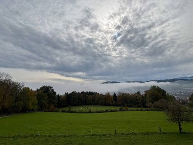 Saint Gallen, İsviçre, 19 Ekim 2024 Sonbaharda yeşil bir tepeden görülen bir vadi üzerindeki toz.