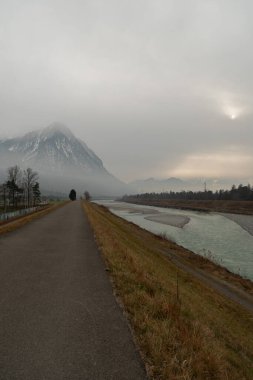 Triesen, Liechtenstein, December 14, 2024 View along the rhine river on a cold and foggy day clipart