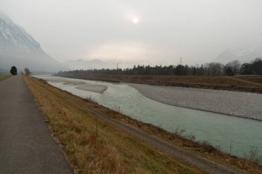 Triesen, Liechtenstein, December 14, 2024 View along the rhine river on a cold and foggy day clipart