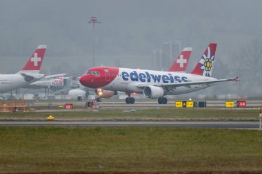 Zürih, İsviçre, 19 Ocak 2025 HB-IJW Edelweiss Airbus A320-214 çok sisli bir günde 28 numaralı pistten kalkıyor.