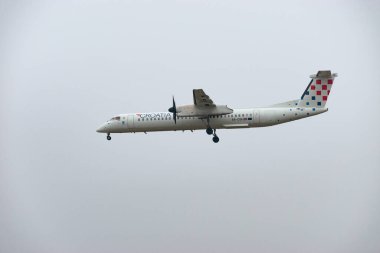 Zurich, Switzerland, January 19, 2025 9A-CQA Croatia Airlines De Havilland Dash 8-400 turboprop aircraft is landing on runway 14 on a very foggy day clipart