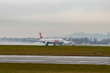 Zürih, İsviçre, 22 Ocak 2025 HB-JNJ İsviçre Boeing 777-3DEER uçağı yağmurlu bir günde 16. pistten kalkıyor.