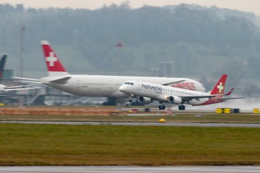 Zürih, İsviçre, 22 Ocak 2025 HB-JVZ Helvetic Havayolları Embraer E195AR uçağı yağmurlu bir günde 28. pistten kalkıyor.
