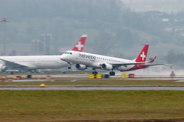 Zürih, İsviçre, 22 Ocak 2025 HB-JVA Helvetic Airways Embraer E195AR uçağı yağmurlu bir günde 28. pistten kalkıyor.