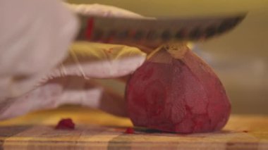 Eldivenli bir kadın pancar kesiyor.